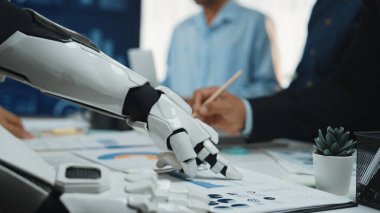 Modern bir ofiste profesyonellerle birlikte çalışan bir robot kol, veri analizini ve takım çalışmasını geliştirir. Bu görüntü teknolojinin ve insan işbirliğinin sinerjisini yakalar. Noogenesis