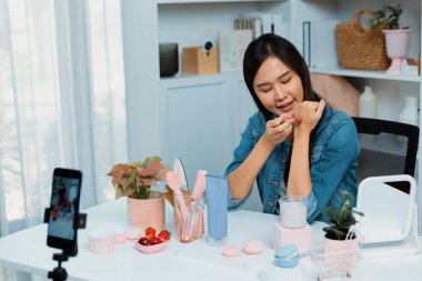 Genç, güzel Asyalı kozmetik makyaj ruju matte pastel rengini modern odadaki sosyal medyada kol testi tanıtımında en çok satanlar listesinde gösteriyor. Taktik.