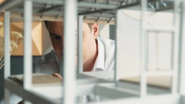 Kafkasyalı mimar mühendisinin yakın çekimi ev inşaatını denetlemek ve bina malzemelerini kontrol etmek. Proje yöneticisi modele dikkatlice bakarken kalemi işaret ediyor. Yönlendirici.