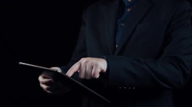 Bir işadamı, elinde bir dizi programlama dili ve kod parçacıklarının bulunduğu bir tablet tutuyor. Teknoloji ve yeniliği sembolize eden, gelecekçi dijital bir arayüzde sergileniyor. Dörtgen