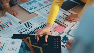 Dinamik iş adamları, modern ofis ortamında etkin bir strateji oluşturmak için finansal verilerin ortak analizine giriştiler, grafikler ve dijital cihazlar kullandılar. SACTR