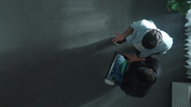 Yöneticinin elinde tablet tutarken yatırımcıyla durduğu ve mali istatistiklere baktığı en düşük bakış açısı. Lider konuşuyor ve tabletteki borsa grafiğinin artması konusunda tavsiyede bulunuyor. Cemaat.