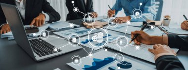 Bir iş ekibi, modern bir şirket ortamında üretkenlik ve büyümeyi sürdürmek için kilit performans göstergelerine odaklanarak belgeler ve dijital veriler üzerinde işbirliği yapmaktadır. Dostluk