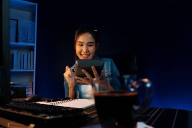 Başarılı genç, güzel Asyalı yaratıcı hesaplama rakamı. Sosyal medyadaki satış hedefi raporundan elde edilen kazanç. Neon ışığı gecesinde yeni bir strateji planlamak için serbest meslek sahibi olmak. Taktik.