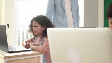 Çeşitli öğrenciler yapay zeka yazılımı kullanırken, Kafkas öğretmeni enerjik çocuğa kodlama konusunda yardım ediyor. Çocuklar oturma ve programlama sistemi. Sevimli bir öğrenci şifreyi öğreniyor. Pedagoji.