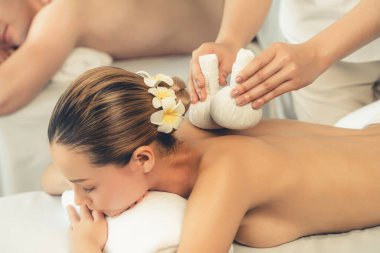 Sıcak bitkisel top spa masaj vücut tedavisi, masör nazikçe bitki torbasını çift müşteri vücuduna bastırıyor. Aromaterapi dinlenme sükuneti ve sükuneti kaplıca salonundaki atmosferi aydınlatıyor. Sessiz.