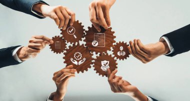 Profesyonellerin elleri, yenilik ve büyüme odaklı bir iş ortamında takım çalışmasını ve etkili strateji gelişimini sembolize ederek, dişlileri işbirliğiyle manipüle eder. Dostluk