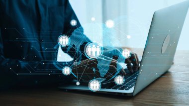 Dijital ağ bağlantılarını ve küresel iletişimi gösteren bir dizüstü bilgisayar üzerinde çalışan bir profesyonel, günümüz çalışma alanındaki teknoloji ve işbirliğinin karışımını gösteriyor. Dörtgen