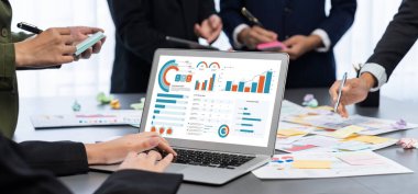 Analizci ekibi yaratıcı ve analitik beyin fırtınası fikri için bilgisayar ekranında BI veri paneli olan yapışkan bir not kullanıyor. Pazarlama stratejisi için finansal veri görselleştirme teknolojisini analiz et. Dahi.