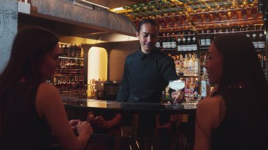 Asyalı akıllı barmen votka bardağını karıştırdı. Çiçek, lüks tezgah barında özel içki yapan güzel müşteriye servis edildi. Ferahlatıcı alkol gece hayatı lüksü. Vinosity.