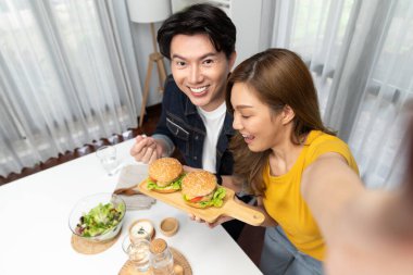 Gülümseyen ev sahibi aşçıların akıllı telefonuyla fotoğraf çekerken üst görüntüsü yemek programında çift hamburger tutarken sosyal medya kanalında ev yapımı salata tabağıyla kolaylıkla görülebiliyor. İnfobahn.