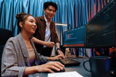 Bilgi teknolojisi geliştiricileri modern ofisteki neon ışık odasında verileri çevrimiçi olarak çalıştıran akıllı web sitesi geliştirme kodlayıcı sistemine işaret ediyorlar. İnfobahn.