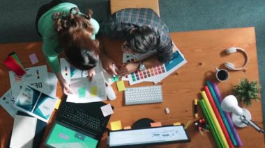 Tasarımcı yazma fikri ekrana bakarken proje yöneticisinin üst görünümü. Akıllı iş adamlarını kapat ve tasarımcı palete bakarken logo tasarımı fikrini açıkla. Sempozyum.