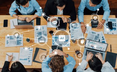 Çeşitli profesyonellerden oluşan bir grup, veri analizi ve yapay zeka kavramları, dizüstü bilgisayarlar ve görsel yardımlar üzerinde yoğunlaşmış bir ortak toplantıda yer alıyor. Dostluk