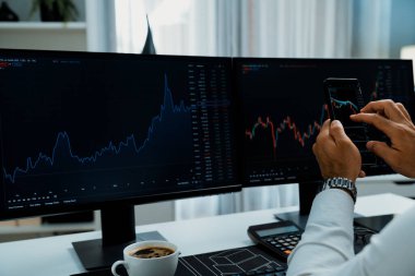 Akıllı telefondan akıllı telefon arayan tüccar işadamı, bilgisayardaki dinamik borsa yatırım ekranını analiz ediyor ve modern merkez ofisteki en kârlı finansal teknoloji pazarına yatırım yapıyor. Tahmin et..