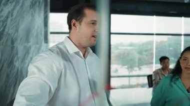 Yetenekli işadamı, cam duvara renkli yapışkan notlar yapıştırarak proje yöneticisine pazarlama fikrini sundu. Proje yöneticisi yatırımcıya projeyi gösteriyor, anlatıyor, gösteriyor. Yönlendirici.