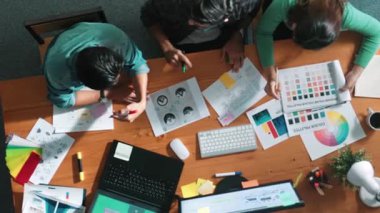 Takım ayakta dikilirken ve yorum yaparken müdürün fikir yazma konusunda üst düzey görüşü. Profesyonel tasarımcı logosu renk paletine bakarken ve renkli kalemle fikri kağıda yazarken. Sempozyum.