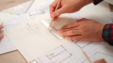 Mimari ekipmanlarla toplantı masasında ev tasarımı üzerine profesyonel mühendis ekibi tartışması ve modern ofiste bina planı dağılımı. Eline odaklan. - Yakın çekim. Tanımlama.