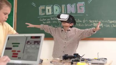 Kız kodlama sistemiyle uğraşırken metaworld 'e elektronik panoyla girmek için VR kulaklık takan bir çocuk. Çeşitli öğrencilerden oluşan bir grup program geliştirmek ve mühendislik kodu yazmak için birlikte çalışıyor. Pedagoji.