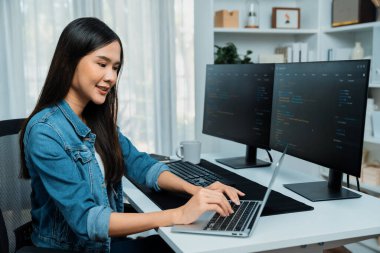 IT geliştiricisinde gülümseyen genç Asyalı dizüstü bilgisayarında kodlama programı verileriyle kotlu tişört giyerek çevrimiçi bilgi yazıyor. Güvenlik analizi iki ekran ile çevrili. Taktik.