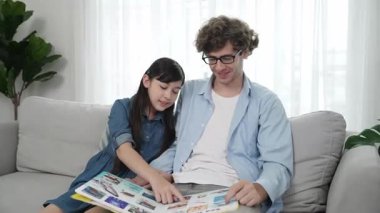 Komik liseli kız masal kitabına işaret ederken mutlu bir baba hikâyesi ve dokunaklı bir jest. Öğrenciler ebeveyn ararken peri kuyruğu hakkında konuşmaktan zevk alırlar. Aile eğlence konsepti. Pedagoji.