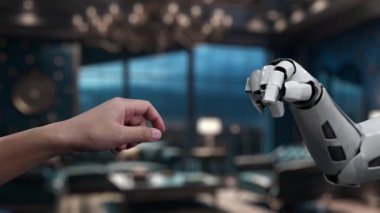 Bir insanın robot kola uzanan elini gösteren çarpıcı bir video modern bir ortamda teknoloji ve insanlık arasındaki işbirliğini ve bağlantıyı sembolize ediyor. Auvana