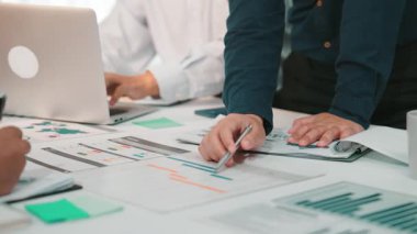 Analiz yapan, raporları inceleyen ve modern bir ofiste dizüstü bilgisayarlar ve belgeler kullanarak stratejiler üzerinde işbirliği yapan farklı kişilerle dinamik bir iş görüşmesi. SACTR