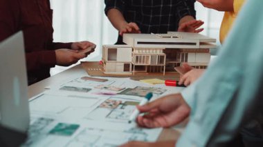 Bir grup mimar modern bir ofiste işbirliği yaparak mimari modeller ve planlar üzerinde tartışırlar. Atmosfer yenilikçi fikirleri ve takım çalışmasını teşvik ediyor. SACTR