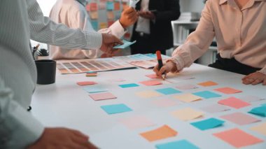 Masada renkli yapışkan notların yer aldığı modern bir ofiste dinamik ve işbirlikçi bir takım toplantısı düzenleniyor. Katılımcılar beyin fırtınası ve planlama seanslarına katılıyorlar. SACTR