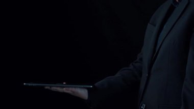 Bir iş adamı interaktif tablet kullanarak dijital pazarlama stratejisi sergiliyor. Karanlık fütüristik arka plan, sergilenen pazarlama kavramlarının yüksek teknoloji hissini arttırır. Dörtgen