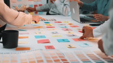 Hareketli bir ofis sahnesinde bir strateji oturumuna katılan işbirlikçi bir ekip sergileniyor. Renkli post-it notları masayı süslüyor, yaratıcı fikirleri ve takım çalışmasını simgeliyor. SACTR