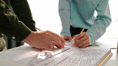 Mimari döküman, ölçüm araçları ve ahşap blokların modern ofiste etrafa saçıldığı masa üzerine planlar yapma konusunda akıllı mimar ve güvenlik mühendisi tartışması. - Yakın çekim. Tanımlama.