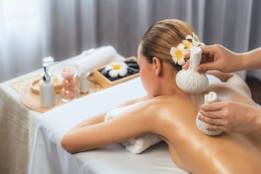 Sıcak bitkisel top spa masaj vücut tedavisi, masör kadın vücuduna nazikçe şifalı bitki torbası bastırıyor. Aromaterapi dinlenme sükuneti ve sükuneti kaplıca salonundaki atmosferi aydınlatıyor. Sessiz.