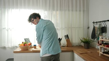 Mutlu baba yemek pişirirken müziğe geçiyor ve modern mutfakta öğle yemeği hazırlıyor. Aktif baba, sebze ve mutfak gereçleri ile çevrili sağlıklı yemek ya da salata yaparken şarkıyla dans ediyor. Pedagoji.