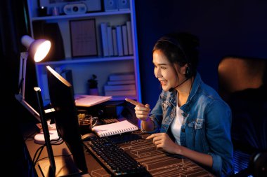 Sunucu kanalı Asyalı etkileyicisi canlı yayında konuşuyor. Sosyal medyada kulaklık takıyor, bilgisayar kaydı yapıyor, dinleyicileri selamlıyor ve Neon Modern Stüdyoları 'nda online olarak koçluk yapıyor. Taktik.