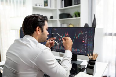 Akıllı tüccar işadamı, modern merkez ofisindeki araştırma pazarında en yüksek kârlı finansal teknolojiye yatırım yaparak bilgisayar üzerinde iki dinamik borsa yatırım ekranını analiz ediyor. Tahmin et..