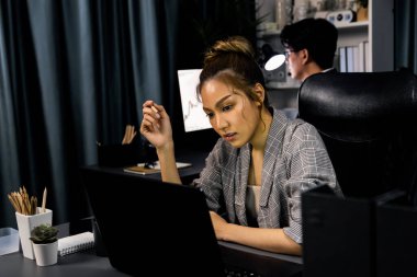 Modern ofiste gece geç saatlerde arka tarafta çalışan iş arkadaşı ile birlikte veri analizi sosyal medya çevrimiçi proje işini rapor etmek için bilgisayara odaklanan iş kadınının ciddi yüzü. İnfobahn.
