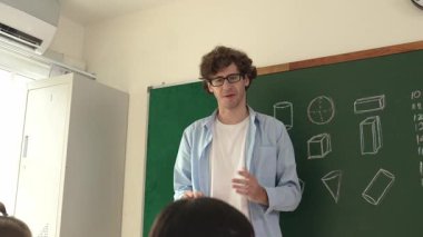 Zeki öğretmen sınıfta fikri açıklarken matematik teorisine işaret ediyor. Profesyonel eğitmen, öğrenciye bakıp matematik dersinde tahtaya basarak fikir hakkında konuşuyor. Pedagoji.