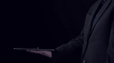 Bir kişi, dijital teknolojinin finansal yönetime entegrasyonunu ve etkin planlama uyumunu sembolize eden, parlayan vergi simgelerini gösteren bir tablet tutuyor. Dörtgen