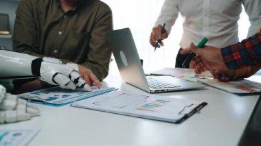 Araştırma ve veri analizi üzerine bir iş adamıyla birlikte çalışan yapay zeka asistanı, karar verme süreçlerindeki akıllı otomasyona geçişi sembolize ediyor. Noogenesis Yapay Zeka