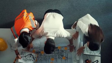 Proje yöneticisi ve inşaat mühendisinin dizüstü bilgisayarlarını incelerken bu fikri mimara da açıkla. Akıllı iş adamlarının bina inşaatı hakkında konuştuğu ve beyin fırtınası yaptığı hava görüntüsü. Hizalama.