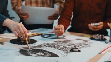 Modern bir çalışma alanında takım çalışmasını ve yenilikleri vurgulayan, bir masanın üzerinde el hareketleriyle hareket eden, işbirlikçi bir tasarım sürecini gösteren dinamik bir sahne. SACTR