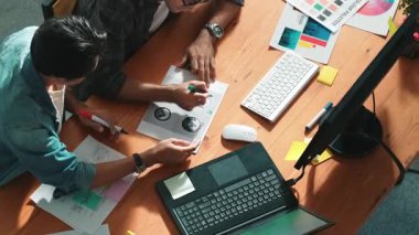 Takım ayakta dikilirken ve yorum yaparken müdürün fikir yazma konusunda üst düzey görüşü. Profesyonel tasarımcı logosu renk paletine bakarken ve renkli kalemle fikri kağıda yazarken. Sempozyum.