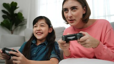 Kafkas anne ve kızı oturma odasında oturup oyun oynuyorlar. Mutlu anne, elinde joystick tutarken akıllı Asyalı kızla vakit geçiriyor. Oyun oynamaktan zevk alıyor. Yaşam tarzı konsepti. Pedagoji.