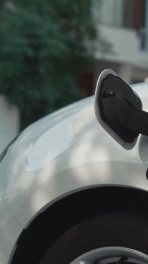 Bir kadın evinde elektrikli araç şarj aletinin fişini çekiyor. İlerici bir yaşam tarzında elektrikli araçların kullanımı, temiz ve sağlıklı bir çevreye katkıda bulunur..