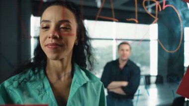 Profesyonel iş adamları yaratıcı pazarlama fikrini modern ofiste tartışırlar. İş adamları cam tahtada yapışkan notlar kullanarak finansal plan üzerinde çalışıyor. Yönlendirici.