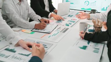 Çeşitli bir iş ekibi, modern bir ofiste grafik ve grafikleri analiz ederken, veri odaklı karar verme üzerine odaklanarak işbirlikçi tartışmalara giriyor. SACTR