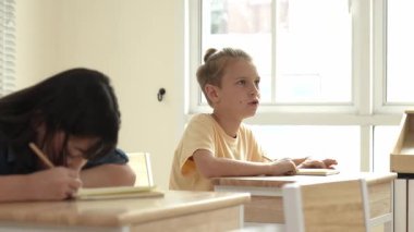Zeki öğrenci sınıfta otururken öğretmenlerin sorularına cevap verir. Tahtaya bakarak ve ilköğretim sınıfına katılarak çeşitli çocuklar öğreniyor ve öğreniyor. Eğitim konsepti. Pedagoji.