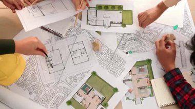 Mimari belge, ölçüm aracı ve ahşap blokların modern ofiste etrafa saçıldığı bir masa üzerinde yapı inşaatı ile ilgili mimar ve güvenlik mühendisi tartışması. Tanımlama.