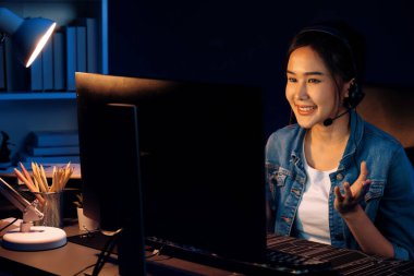 Sunucu kanalı Asyalı etkileyicisi canlı yayında konuşuyor. Sosyal medyada kulaklık takıyor, bilgisayar kaydı yapıyor, dinleyicileri selamlıyor ve Neon Modern Stüdyoları 'nda online olarak koçluk yapıyor. Taktik.